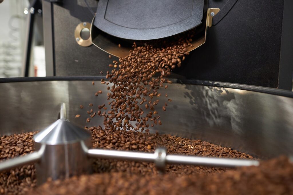 background of fresh coffee beans spilling from industrial coffee roaster